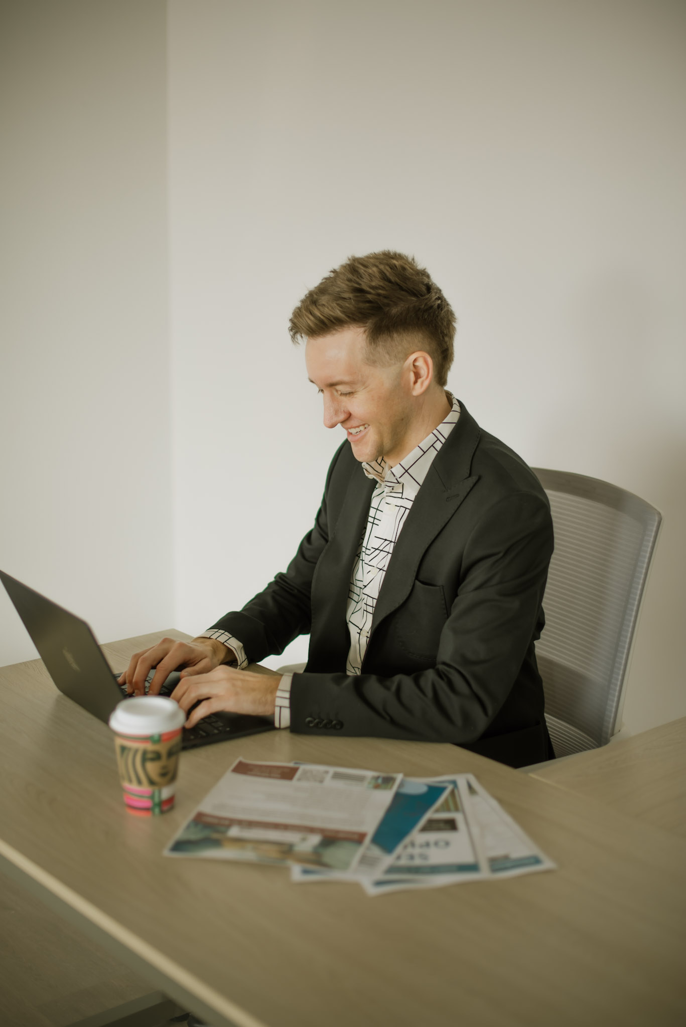 Cody Miller working at his desk with a laptop and mortgage paperwork