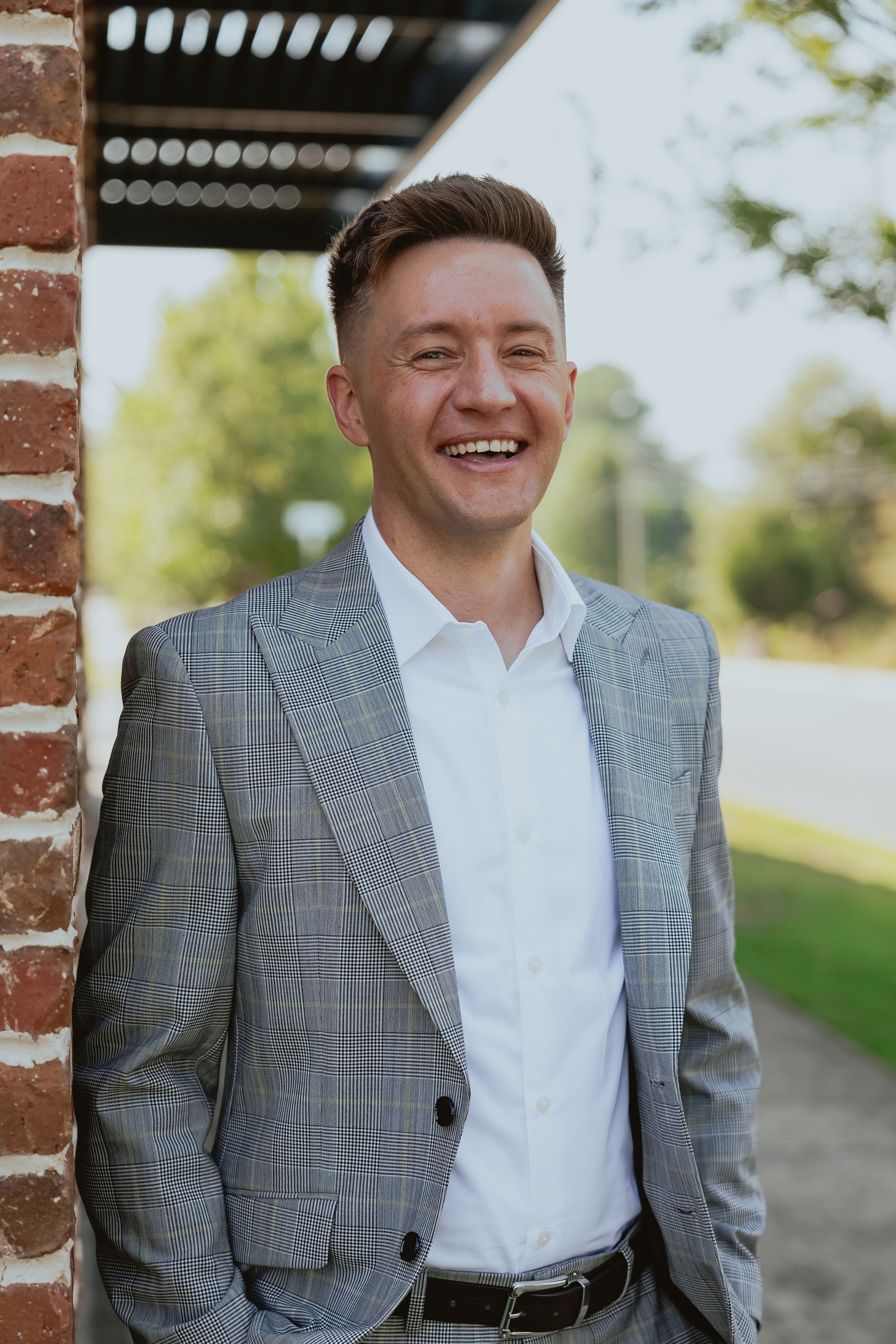 Portrait of Cody Miller leaning against a brick wall, smiling